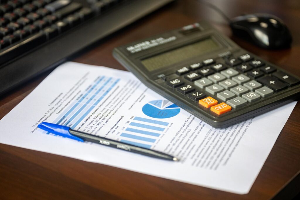 Calculator, rapoarte financiare tipărite și un pix pe biroul unei firme mici